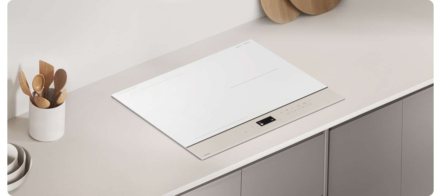 그레이톤 우드 패널에 그레이 톤 대리석 상판이 깔린 주방 테이블이 보입니다. 테이블 가운데에는 BESPOKE 전기 레인지가 설치되어 있습니다. 전기레인지 왼쪽에는 회색 화병과 검은색 세제 통이 보이고 오른쪽 상단으로는 흰색 원통 모양의 도자기 수저 통 안에 원목 수저가 꽂혀 있습니다.