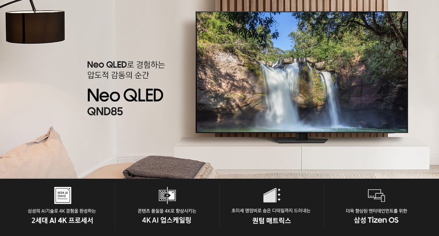 장식장 위에 TV가 설치되어 있습니다. 화면에는 폭포가 떨어지는 자연풍경이 보입니다. Neo QLED로 경험하는 압도적 감동의 순간 Neo QLED QND85 KV입니다. 하단에는 삼성의 AI기술로 4K 경험을 완성하는 2세대 AI 4K 프로세서, 초미세 명암비로 숨은 디테일까지 드러내는 퀀텀 매트릭스, 콘텐츠 품질을 4K로 향상시키는 4K AI 업스케일링, 더욱 향상된 엔터테인먼트를 위한 삼성 Tizen OS 문구와 아이콘이 있습니다.