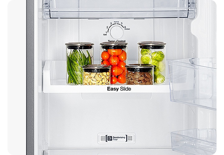 냉장고 하칸 내상 이지 슬라이브 선반 위에 반울양배추와 방울 토마토, 견과류 등이 담긴 병이 놓여있습니다.