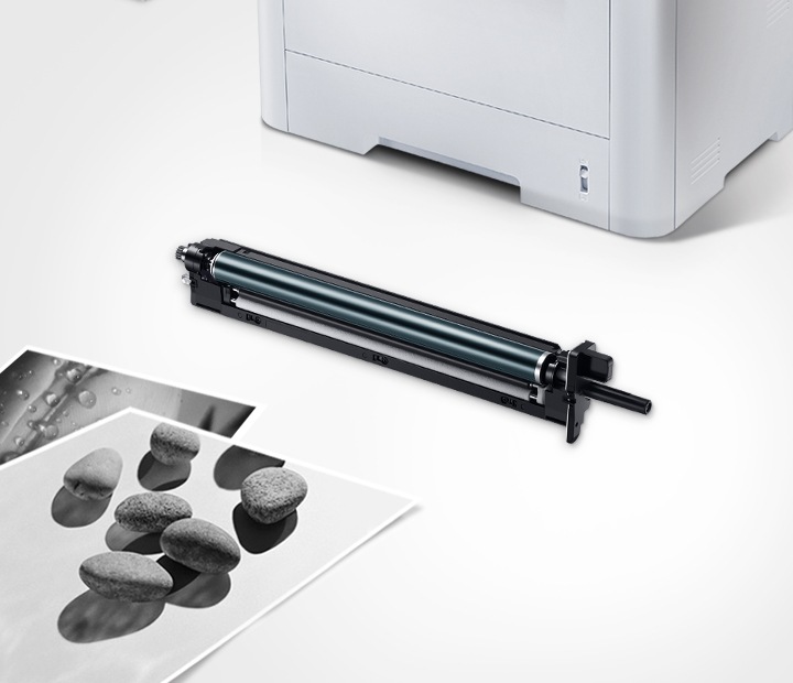 위쪽 삼성 프린터에서 출력물이 나오고 있고, 아래쪽 삼성 토너 카트리지가 있습니다.