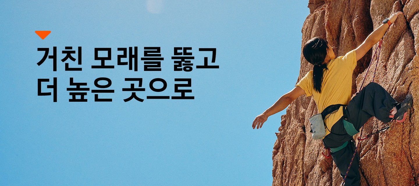 한 여성이 갤럭시 워치 울트라를 손목에 차고 암벽등반을 하고 있습니다. 거친 모래를 뚫고 더 높은 곳으로