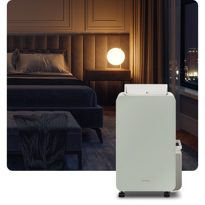 불이 꺼진 침실 안 침대 옆 원형 조명 하나가 켜져있고  앞에 삼성 인버터 제습기가 서 있습니다.
