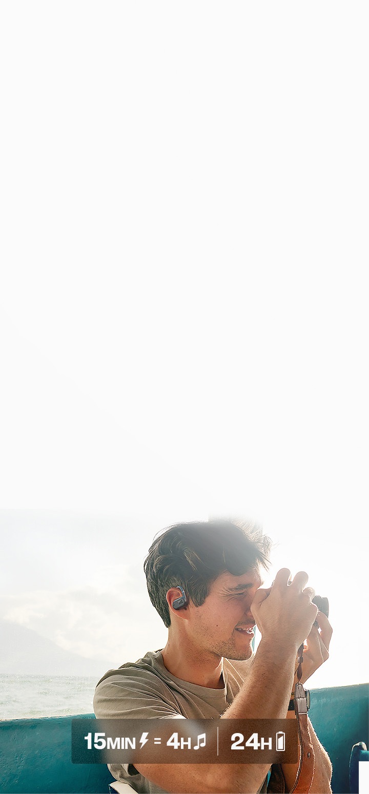 배 안에서 남성이 이어폰을 착용한 상태로 카메라로 어딘가를 촬영하고 있습니다, 남성 뒤에는 바다가 보이고 있습니다.