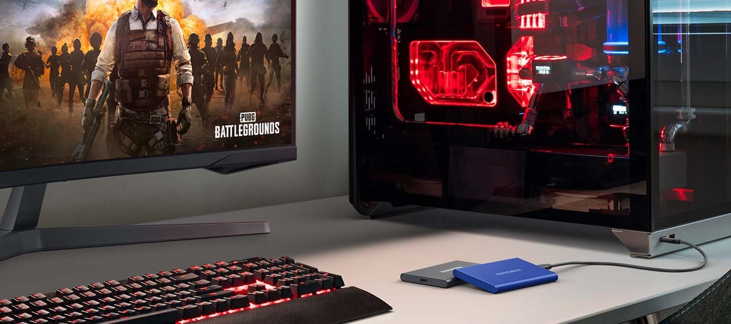 약간 어두운 책상을 비스듬히 바라본 배경으로 이미지 왼쪽 부분에 책상 위에는 키보드와 게임이&nbsp;켜져 있는&nbsp;모니터 이미지가 보이고 있고 이미지 오른쪽 부분에는 외장 SSD가 케이블로 연결된 컴퓨터 본체가 보이고 있는&nbsp;이미지입니다.