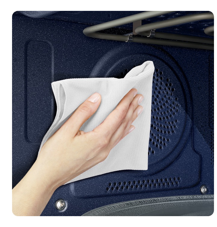 Bespoke 직화오븐 35L 의 내부 조리실 벽면이 확대되어 보여지고 있으며, 마른 수건으로 벽면을 닦고 있는 사람의 손이 보여지는 연출된 이미지입니다.