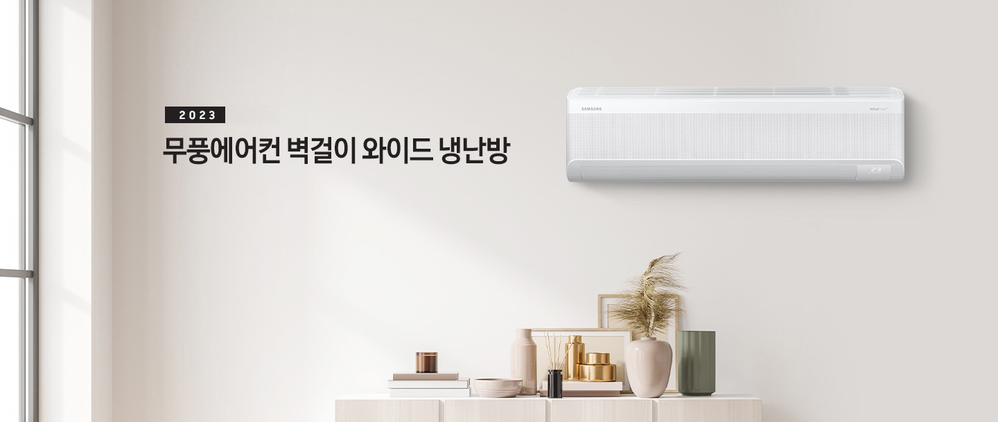 밝은 하얀 톤의 거실에 왼쪽 상단에 무풍에어컨 벽걸이 와이드 냉난방 타이틀이 적혀있고 오른쪽에 벽걸이 와이드 에어컨이 배치되어 있는 모습이다. 하단에는 장식장이 있는 모습이다.