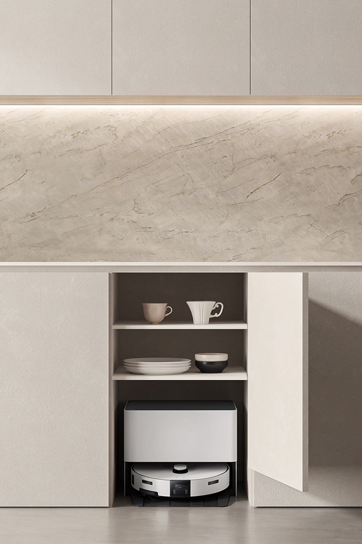 베이지톤 주방의 싱크대 하부 수납장 중 한 칸이 열려있고 그 안에는 컵과 그릇이,  최하단에는 Bespoke AI 스팀 울트라 자동 급배수 제품이 있다