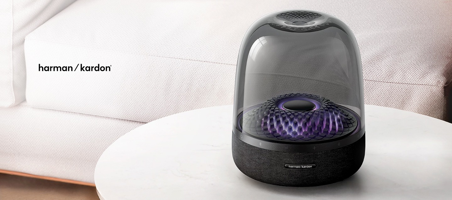 밝은 실내 거실에 흰색 소파가 있고 앞에 테이틀 위에 aura studio4 제품이 놓여있습니다.