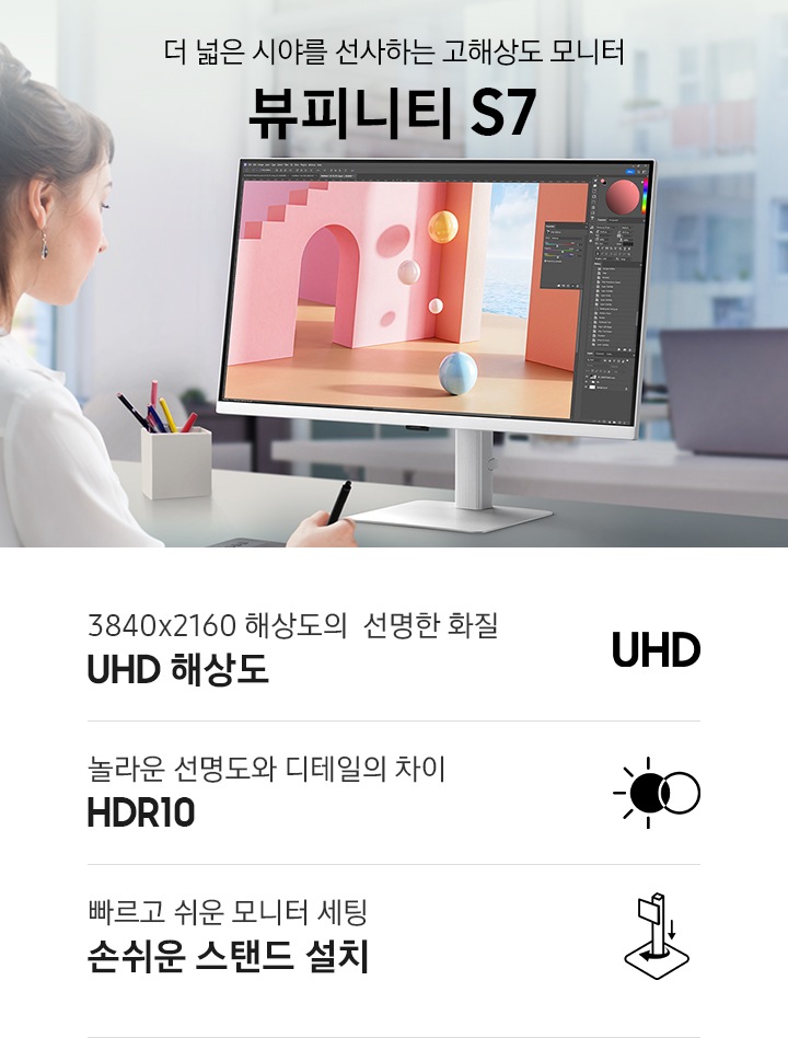 한 여성이 컴퓨터 앞에서 포토샵을 이용해 디자인 작업중인 모습이 보입니다. 데스크에는 모니터와 펜 타블릿, 연필꽂이와 색상샘플 등이 보입니다. 