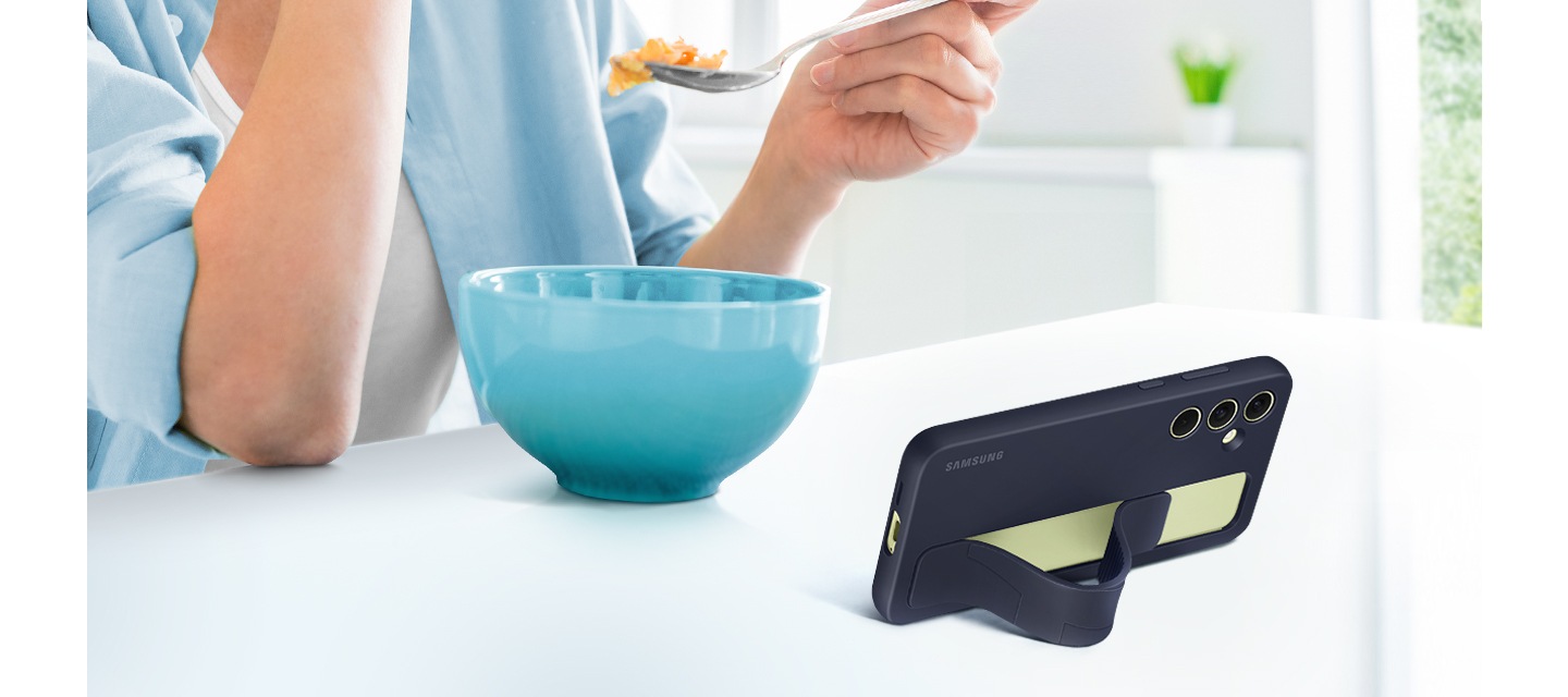 스탠딩 그립 케이스를 씌운 갤럭시 기기를 보며 시리얼을 먹고 있는 사람이 있습니다. 기기는 편안한 시야각을 확보할 수 있도록 수평으로 세워져 있습니다.