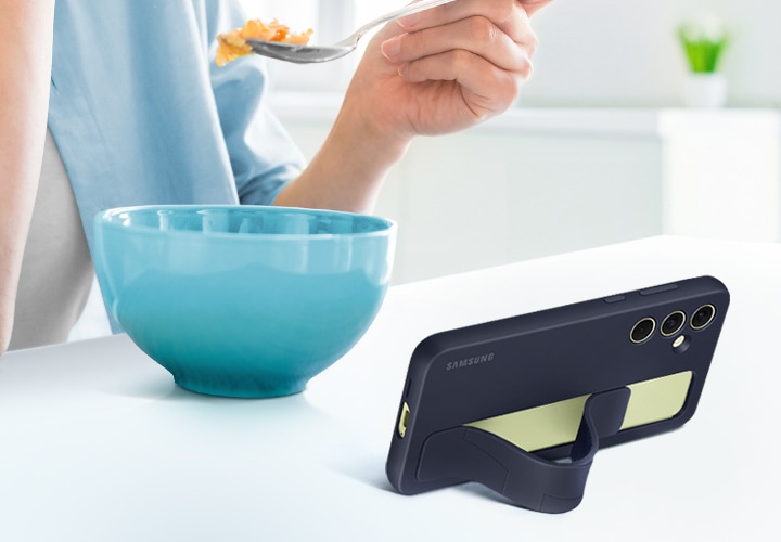 스탠딩 그립 케이스를 씌운 갤럭시 기기를 보며 시리얼을 먹고 있는 사람이 있습니다. 기기는 편안한 시야각을 확보할 수 있도록 수평으로 세워져 있습니다.