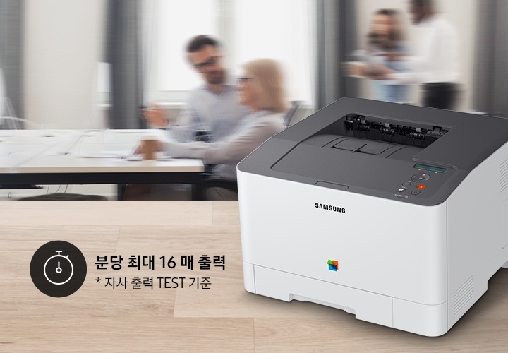 제품이 측면으로 우드 책상 위에 올려져 있고, 그 뒤에는 회의를 하는듯한 배경 이미지가 블러 처리되어 있습니다.