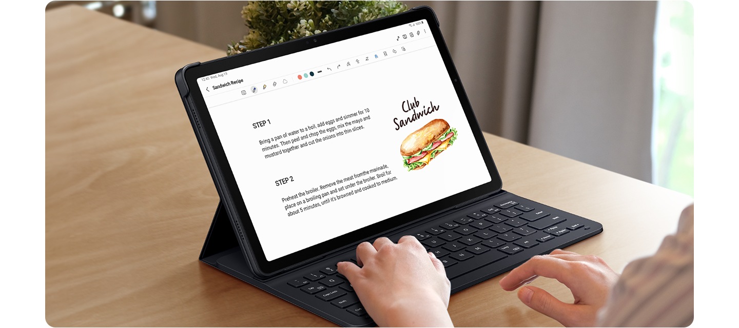 책상 위에 슬림 키보드 북커버를 장착한 갤럭시 탭 A9+로 타이핑하고 있는 모습입니다. 화면에는 클럽 샌드위치 레시피가 표시되고 있습니다.