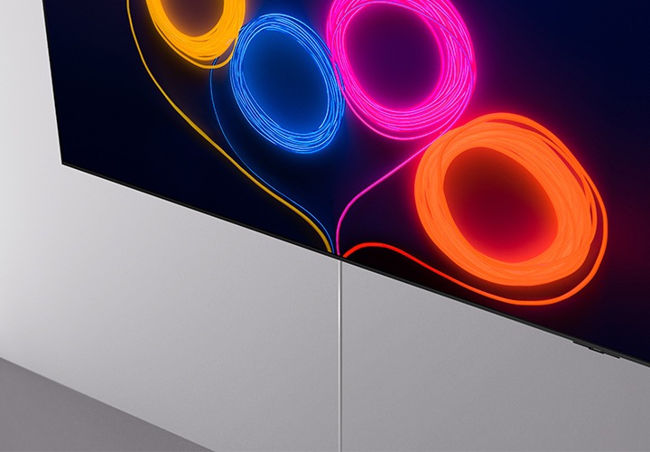 벽에 TV가 설치되어 있으며, 화면에는 노란색, 파란색, 분홍색, 주황색 선들이 동그랗게 되어있며 선 끝이 TV 하단으로 향하고 있습니다. TV 하단에는 게이블 선이 보입니다.