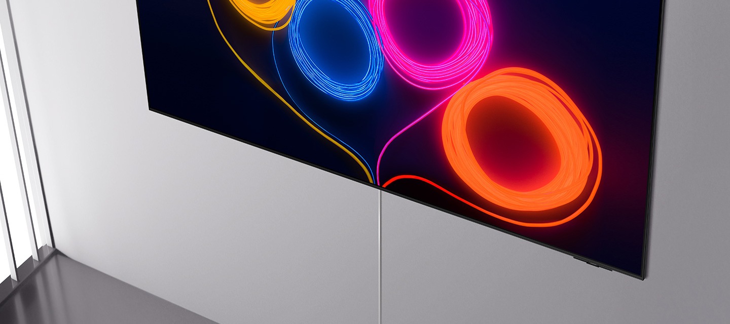 벽에 TV가 설치되어 있으며, 화면에는 노란색, 파란색, 분홍색, 주황색 선들이 동그랗게 되어있며 선 끝이 TV 하단으로 향하고 있습니다. TV 하단에는 게이블 선이 보입니다.