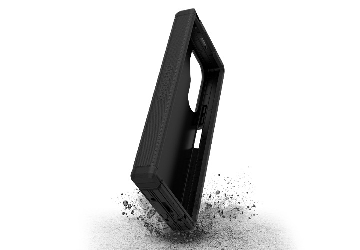 거친 바닥을 배경으로 갤럭시 Z 폴드6 오터박스 디펜더 엑스티 케이스가 떨어지는 이미지가 보이고 있습니다.