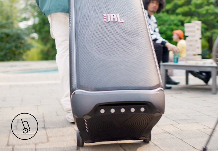 야외에서 사람이 제품을 캐리어처럼 핸들을 뽑아 캐리어처럼 스피커를 이동시키고 있습니다.