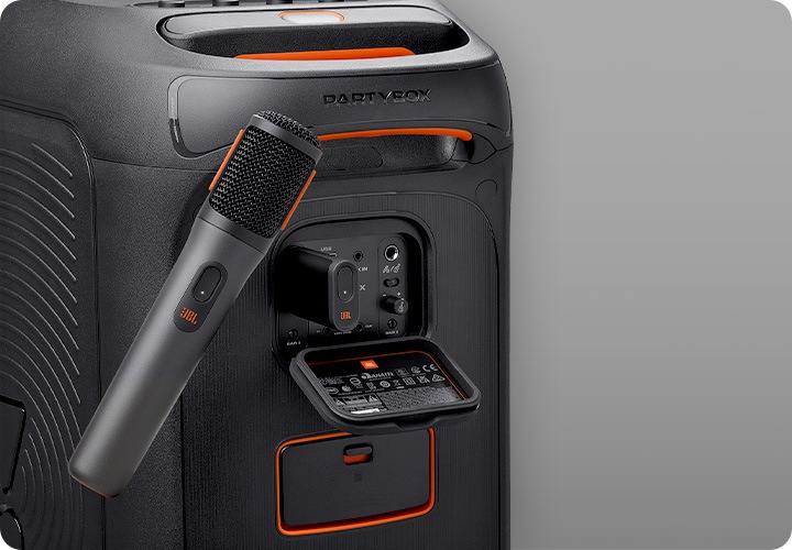 JBL PARTYBOX 스피커 뒤에 동글이 꽂아져 있으며, 그 앞에는 마이크 1개가 보입니다.