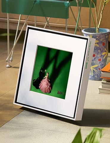 바닥에 뮤직 프레임이 놓여 있습니다. 뮤직 프레임 뒤로는 화분과 책들이 보입니다.