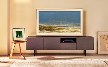 테이블 위에 뮤직 프레임이 놓여 있습니다. 뮤직 프레임 오른쪽에는 장식장이 있으며, 그 위에는 TV가 놓여 있습니다.