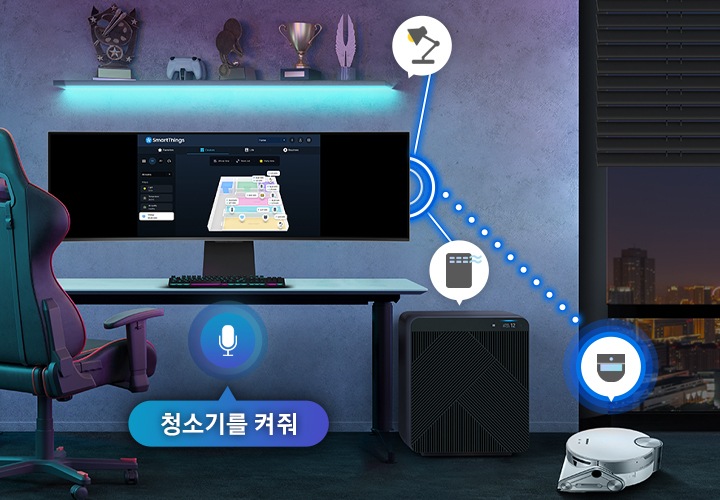 방과 같은 공간입니다. 방 안에는 노을이 진 창문, 의자와 책상이 있고 책상 위에는 SmartThings 화면인 모니터와 키보드가 놓여있습니다. 책상 옆에는 공기청정기와 공기청정기 아이콘이 있고 옆에는 로봇 청소기와 로봇청소기 아이콘이 있습니다. 모니터 위에는 스텐드와 스텐드 아이콘이 있고 위에 트로피 장식이 5개 놓여져 있습니다. 테이블 아래에는 마이크 아이콘이 있고 청소기를 켜줘 라는 문구가 써져 있습니다. 