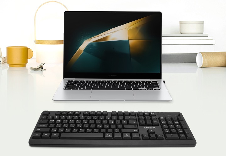 테이블에 노트북이 놓여져 있는 이미지입니다. 노트북 앞에는 키보드가 위치해 있습니다.