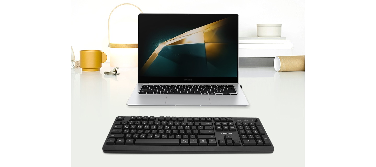 테이블에 노트북이 놓여져 있는 이미지입니다. 노트북 앞에는 키보드가 위치해 있습니다.