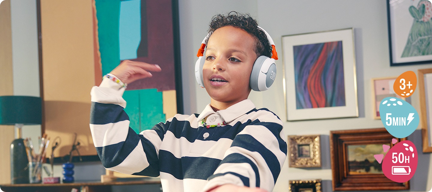 남자 아이가 제품을 착용한 상태로 춤을 추고 있습니다. 아이 뒤 벽에는 액자들이 걸려 있습니다.