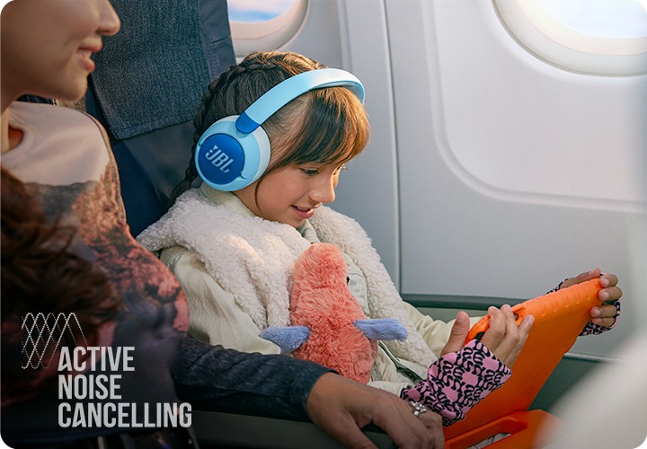 제품을 착용한 여자 아이가 기내에서 태블릿 PC를 보고 있습니다.