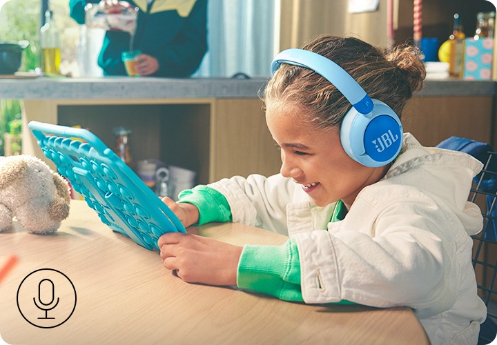 제품을 착용한 여자 아이가 테이블에 앉아 태블릿 PC를 보고 있습니다.