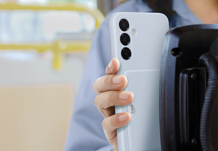 한 여성이 교통비를 결제하기 위해 스마트폰을 태그하고 있습니다. 블루 색상의 카드 슬롯 케이스를 착용한 갤럭시 A16 5G에 카드가 들어있습니다.