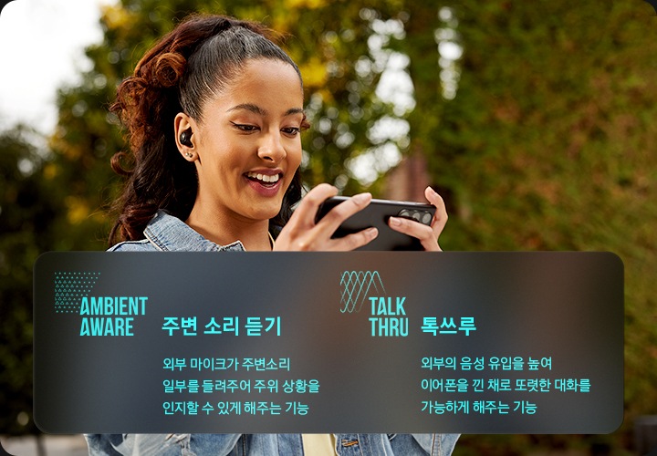 여성이 귀에 제품의 이어버드를 착용한 상태로 스마트폰을 보고 있습니다. 오른쪽에는 앰비언트 기술에 대해 설명이 되어 있습니다. (주변 소리 듣기 : 외부 마이크가 주변소리 일부를 들려주어 주이 상황을 인지할 수 있게 하는 기능 / 톡쓰루 : 듣고 있던 컨텐츠 사운드를 낮추고 외부소리 유입을 현저히 높여 이어폰을 낀 채로 이어폰을 낀 채로 대화할 수 있게 하는 기능)