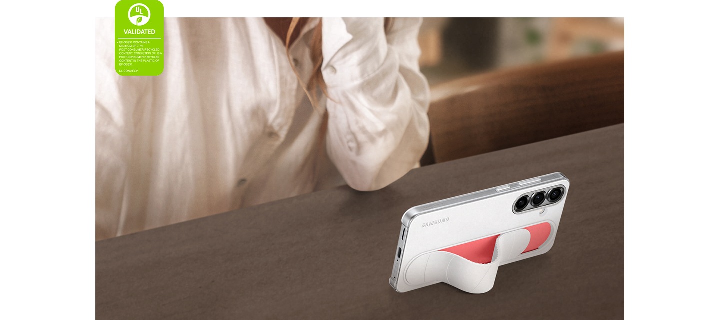 흰색 스탠딩 그립 케이스를 장착한 갤럭시 S25가 기울어진 채 서있습니다. 가로모드로 영상이 재생됩니다. 왼쪽 모서리에는 '스탠딩 그립 케이스는 최소 7.7%의 소비자 재활용 콘텐츠를 포함하고, 케이스에 사용된 플라스틱에는 18% 소비자 재활용 콘텐츠를 포함합니다. UL.COM/ECV' 라고 적힌 UL 환경 클레임 검증 마크가 표시되어 있습니다.