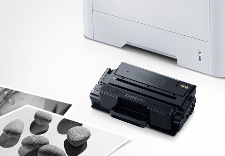 위쪽 삼성 프린터에서 출력물이 나오고 있고, 아래쪽 삼성 토너 카트리지가 있습니다.
