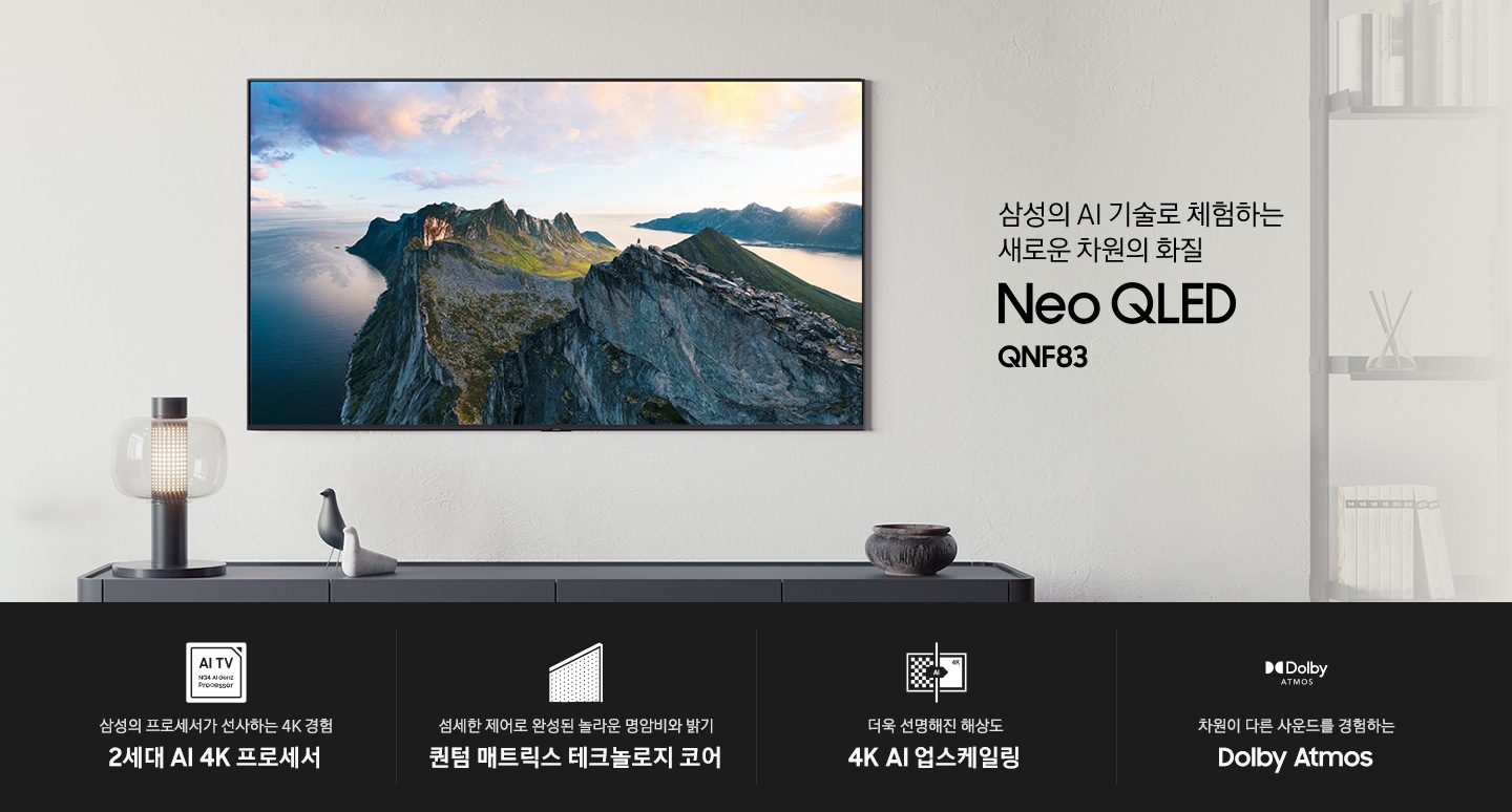 벽에 TV가 설치되어 있습니다. 화면에는 자연 풍경이 보입니다. TV 하단에는 장식장이 보이며 그 위에는 조명과 장식품이 있습니다. 삼성의 AI 기술로 체험하는 새로운 차원의 화질 Neo QLED QNF85 KV입니다. 하단에는 삼성의 프로세서가 선사하는 4K 경험 2세대 AI 4K 프로세서, 섬세한 제어로 완성된 놀라운 명암비와 밝기 퀀텀 매트릭스 테크놀로지 코어, 더욱 선명해진 해상도 4K AI 업스케일링, 좋아하는 콘텐츠를 실감나는 사운드와 함께 Dolby Atmos 문구와 아이콘이 있습니다.