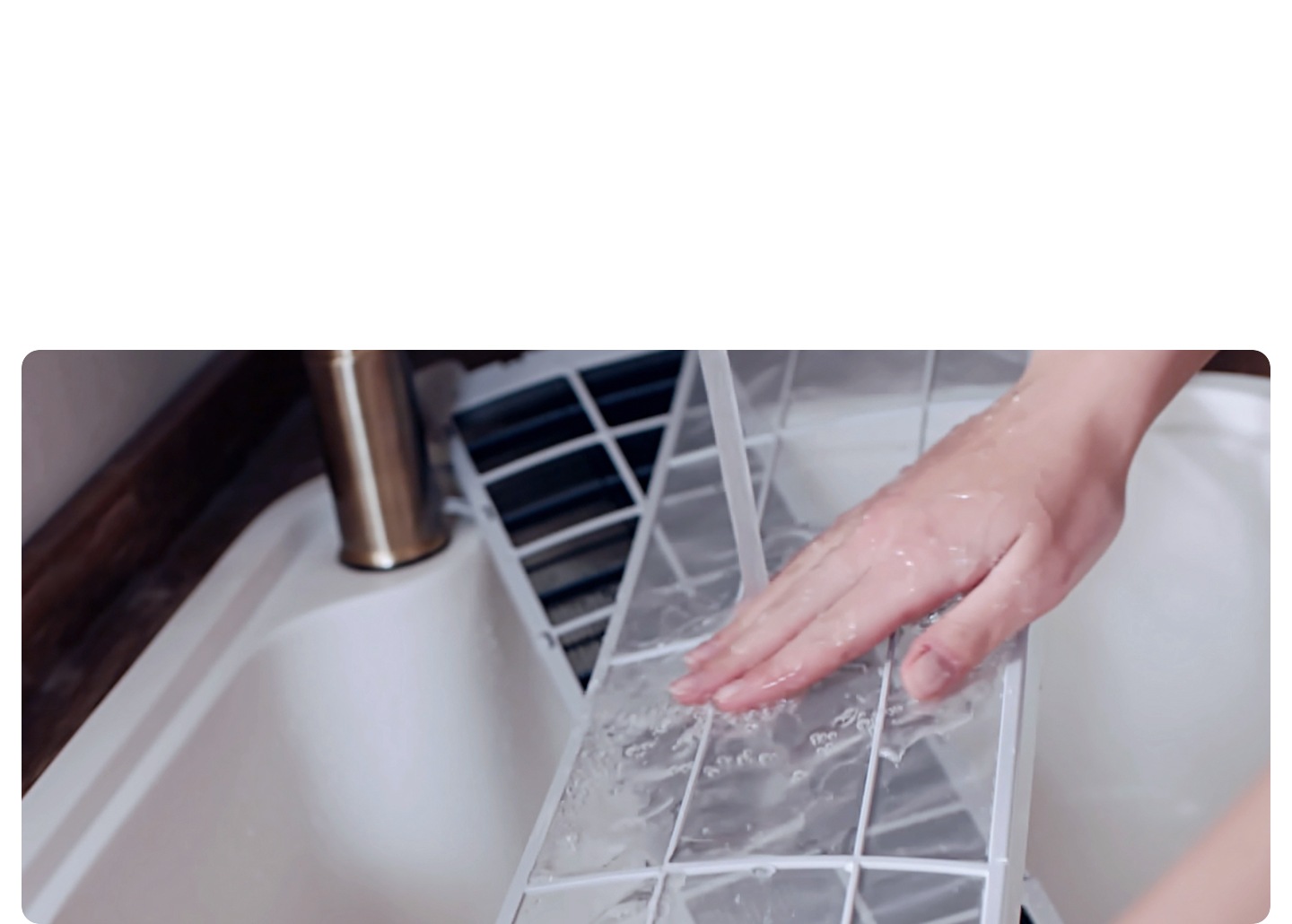 세며대에 벽걸이 에어컨 필터를 손으로 세척하는 듯한 모습이 보여집니다.