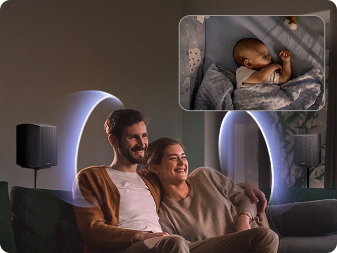 상단에는 여성과 남성이 소파에 앉아 있으며, 뒤에 리어 스피커에서 음파가 나오고 있습니다. 오른쪽 상단에는 아기가 침대에서 잠들어 있습니다.