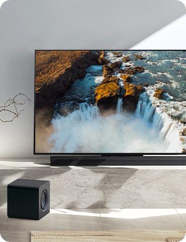 장식장 위에 TV와 사운드바가 설치되어 있으며, 장식장 왼쪽 앞에 서브 우퍼가 놓여 있습니다.