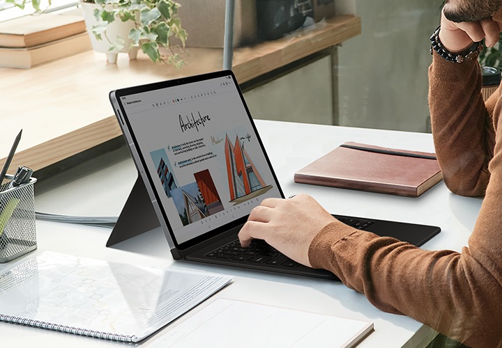 한 남성이 키보드 북커버에 손을 올리고 갤럭시 탭 S10 S10 FE+를 사용하고 있습니다.