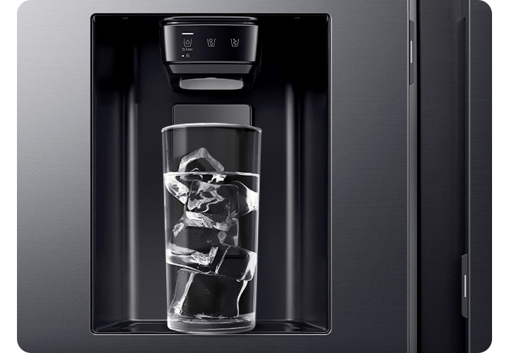 냉장고 외상 아이스메이커 부분이 확대되어 있습니다. 얼음이 나오는 디스펜서 아래에 물이 담긴 유리컵이 들어있고 얼음이 가득 들어있는 연출 이미지 입니다.