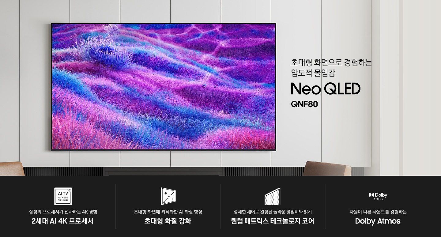 벽에 TV가 설치되어 있습니다. 초대형 화면의로 경험하는 압도적 몰입감 Neo QLED QNF80 KV입니다. 하단에는 삼성의 프로세서가 선사하는 4K 경험 2세대 AI 4K 프로세서, 초대형 화면에 최적화한 AI 화질 향상 초대형 화질 강화, 섬세한 제어로 완성된 놀라운 명암비와 밝기 퀀텀 매트릭스 테크놀로지 코어, 차원이 다른 사운드를 경험하는 Dolby Atmos 문구와 아이콘이 있습니다.