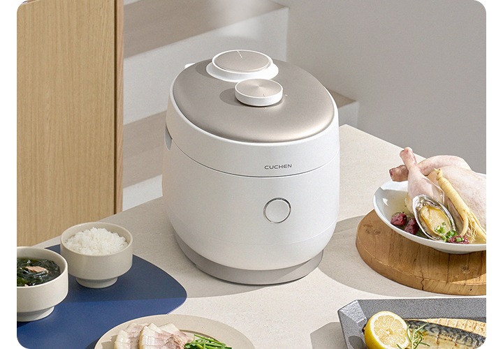 쿠첸 IOT 밥솥에서 김이 올라오고 있으며 밥솥 주변에 다양한 식사거리가 있는 이미지가 보이고 있습니다.