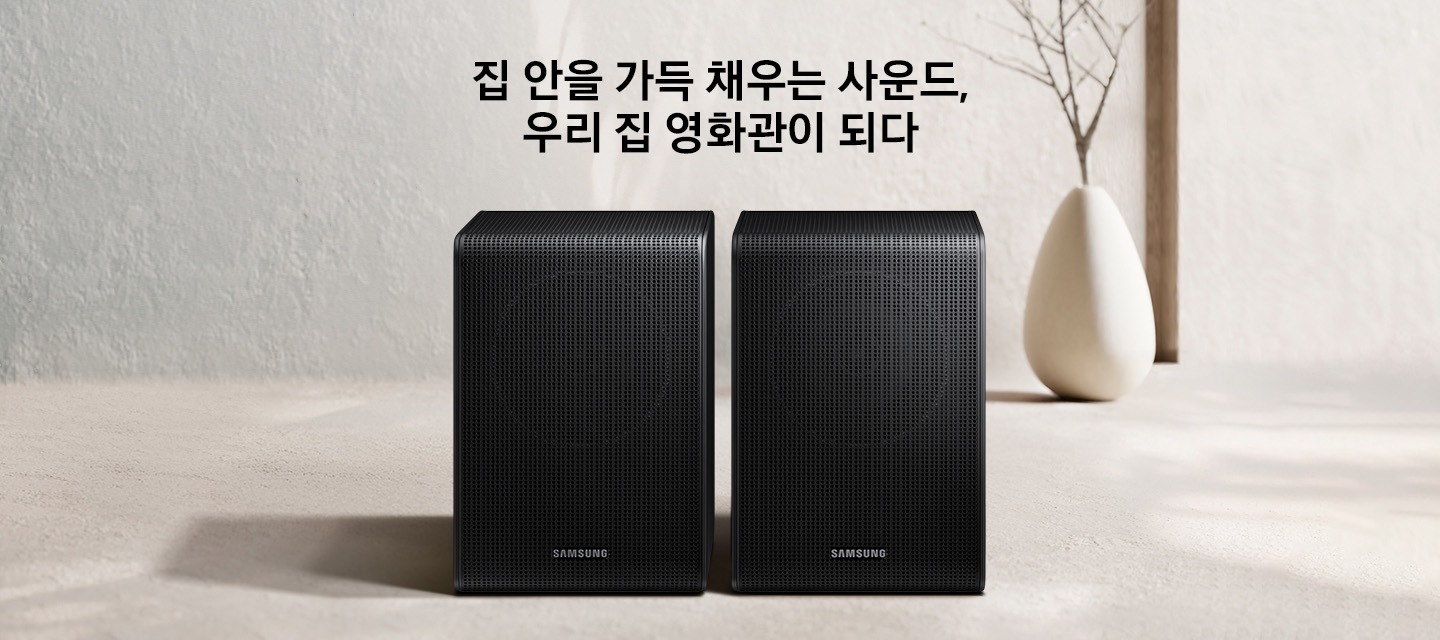 무선 리어스피커가 놓여 있습니다. 스피커 뒤로는 화병이 보입니다. 집 안을 가득 채우는 사운드, 우리 집 영화관이 되다. 무선 리어스피커 KV입니다.