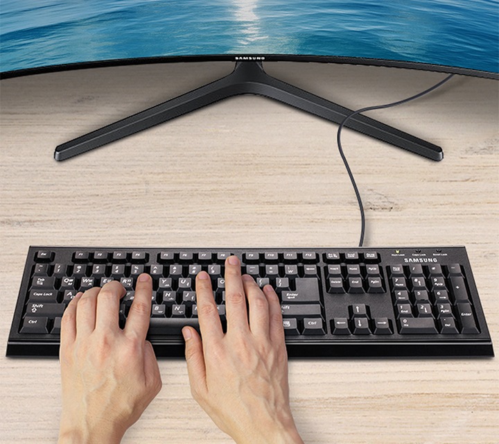 정면에 모니터와 검은색 키보드가 보이며 키보드에 양 손을 올려 둔 이미지가 보입니다.	