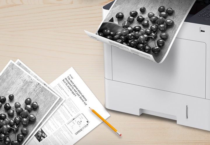 좌측 아래에 출력된 인쇄물이 놓여있고, 우즉 상단에 프린터와 프린터에서 양면 인쇄되는 인쇄물이 나오고 있습니다.