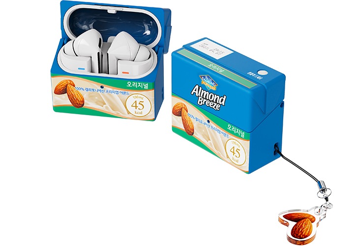 좌측에 버즈 제품이 아몬드 브리즈 오리지널 케이스가 장착된 채 뚜껑이 열려있으며, 우측에 아몬드 키링이 달린 뚜껑이 닫힌 아몬드 브리즈 오리지널 케이스가 보이고 있습니다. 