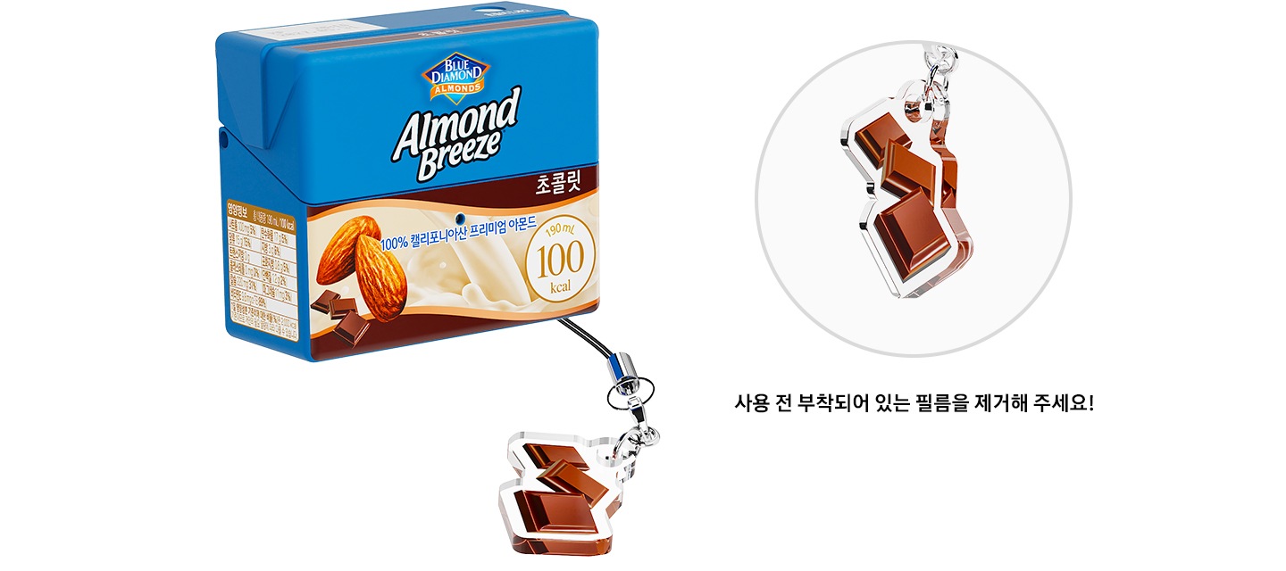 좌측에 초콜릿 키링이 달린 아몬드 브리즈 초콜릿 케이스가 보이고, 우측에 초콜릿 키링을 상세히 보여주고 있습니다. 초콜릿 키링 하단에 ＂사용 전 부착되어 있는 필름을 제거해 주세요!”라는 텍스트가 있습니다.