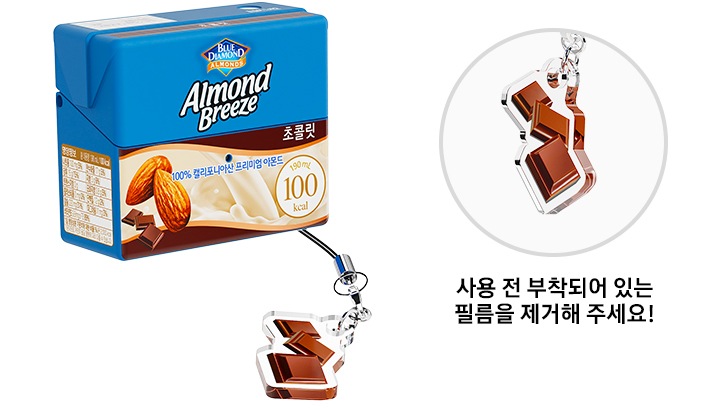 좌측에 초콜릿 키링이 달린 아몬드 브리즈 초콜릿 케이스가 보이고, 우측에 초콜릿 키링을 상세히 보여주고 있습니다. 초콜릿 키링 하단에 ＂사용 전 부착되어 있는 필름을 제거해 주세요!”라는 텍스트가 있습니다.