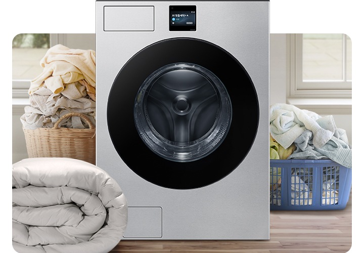 Bespoke AI 세탁기가 중앙에 나와있고 좌측 뒷편 라탄 바구니에 의류가 가득 쌓여있고 앞쪽에 이불이 나와있습니다. 우측 파란색 플라스틱 바구니에도 수건 등 각종 옷감이 가득 쌓여있는 연출된 이미지입니다.