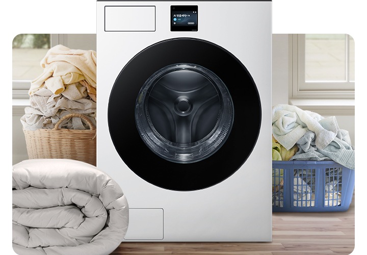 Bespoke AI 세탁기가 중앙에 나와있고 좌측 뒷편 라탄 바구니에 의류가 가득 쌓여있고 앞쪽에 이불이 나와있습니다. 우측 파란색 플라스틱 바구니에도 수건 등 각종 옷감이 가득 쌓여있는 연출된 이미지입니다.